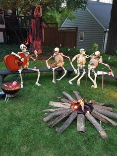 skeletons sitting around a fire pit in the yard with guitars and drums on it's legs