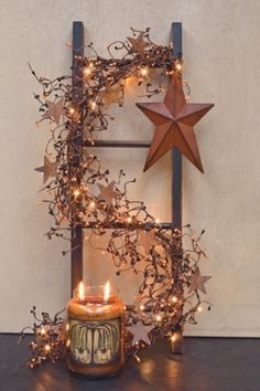 two lit candles are sitting in front of a star and wreath with branches on it