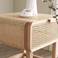 a white vase sitting on top of a wooden table next to a cup and saucer