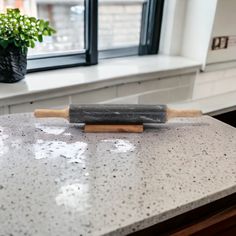 a rolling pin sitting on top of a kitchen counter next to a potted plant