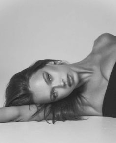 a black and white photo of a woman laying on the floor with her arms behind her head