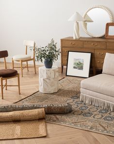 a living room filled with furniture next to a wooden dresser and mirror on top of a hard wood floor