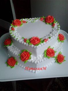 a three tiered cake with red roses on the top and green leaves around it