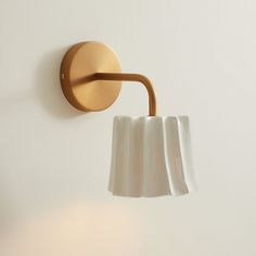 a wall light that is on the side of a white wall with a brown arm