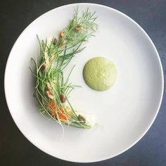 a white plate topped with green food next to a small piece of broccoli