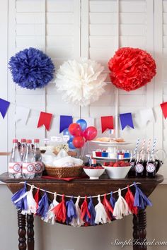 a table topped with lots of red, white and blue paper pom poms