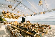 an outdoor dining area on the beach with tables and chairs set up in front of it