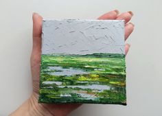 a hand holding a small piece of art that looks like it has green paint on it