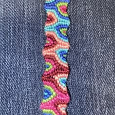 a close up of a colorful tie on someone's jeans