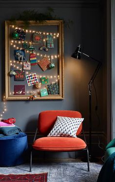 a red chair sitting next to a blue ottoman in front of a painting on the wall