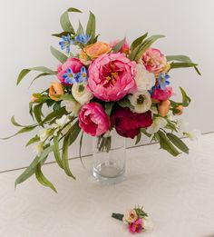 a vase filled with lots of flowers on top of a white table next to a flower arrangement