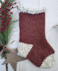 a red and white knitted stocking next to christmas decorations