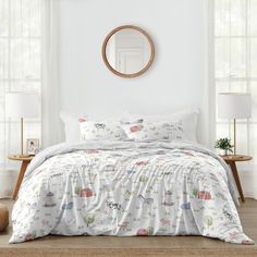 a bed with white comforter and pillows in a bedroom next to a round mirror