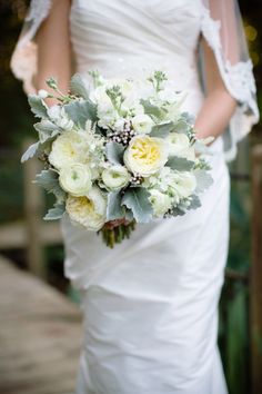 a bride holding a bouquet of white and yellow flowers