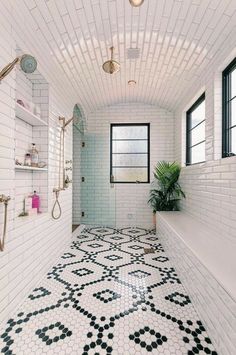 a white bathroom with black and white tiles on the floor, shower, and tub