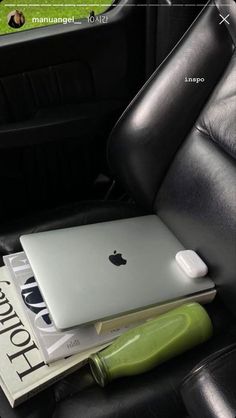 an apple laptop sitting on top of a book in the back seat of a car