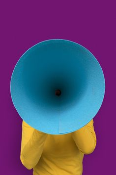 a person with a large blue object on their head in front of purple and yellow background