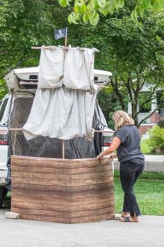 a woman standing next to a wooden barrel with a boat on it's back