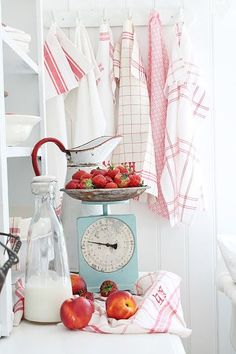 a kitchen scale with apples and strawberries on it next to a bottle of milk