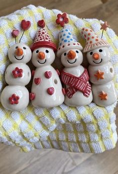 three snowmen with hats and scarves are sitting on a towel