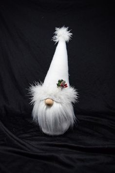 a white gnome's hat with red berries on the top is sitting on a black background