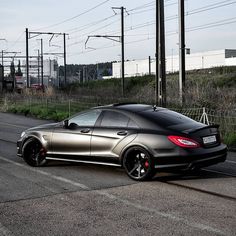 a silver mercedes cls parked on the side of the road in front of power lines