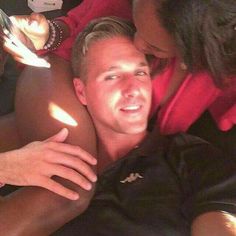 a man laying on top of a bed next to a woman in a red shirt