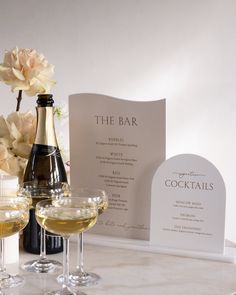 two glasses of champagne and a bottle of wine on a table next to a menu