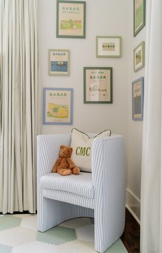 a teddy bear sitting on a chair in front of a wall with pictures and frames