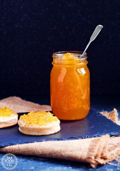 a jar filled with orange marmalade sitting on top of a blue cloth next to crackers