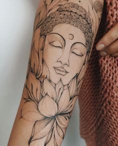 a woman's arm with a buddha tattoo on it and a flower in the middle