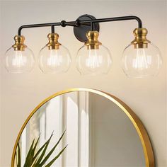 three light bathroom fixture with clear glass globes and gold accents on the vanity mirror