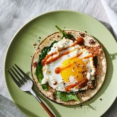 an egg is on top of a tortilla with spinach and tomato sauce