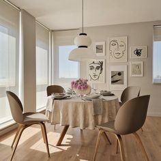 a dining room table with plates and bowls on it, in front of large windows