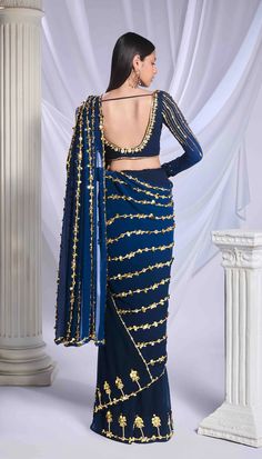 Our midnight blue pre-stitched saree, expertly crafted from a blend of georgette and tulle fabrics, features a delicate floral border adorning the tulle bottom, while the georgette pallu is elegantly embroidered with lines of pearls, metallic details, and acrylics. Paired with this saree is a georgette full-sleeve blouse, featuring metallic motifs and embellished with lines of pearls, golden bricks, and intricate motifs.From Papa Don’t Preach’s Bring Your Own Fairytale collection. DELIVERY TIMEP Blue Traditional Pre-draped Saree For Party, Blue Pre-draped Saree For Festive Evenings, Blue Bollywood Style Formal Blouse Piece, Blue Bollywood Blouse For Formal Occasions, Blue Bollywood Formal Blouse Piece, Blue Bollywood Pre-draped Saree For Evening, Blue Pre-draped Saree With Resham Embroidery For Party, Blue Georgette Pre-draped Saree For Evening, Blue Pre-draped Saree With Zari Work For Evening