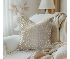 a white couch sitting next to a lamp on top of a hard wood floor covered in pillows