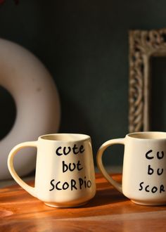 two coffee mugs that say cute but scorpic and curvy score