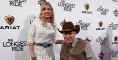 a man standing next to a woman in a white dress and cowboy hat on the red carpet