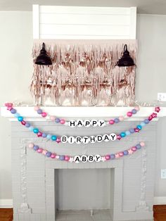 a birthday party with balloons and streamers hanging from the fireplace mantel, along with decorations