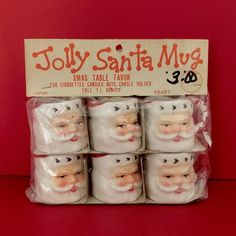 six white santa mugs in plastic wrappers on a red surface with an advertisement for jolly santa mugs