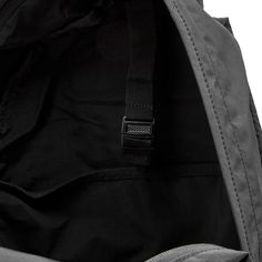 the back pocket of a black backpack with a zipper on it's side and two straps