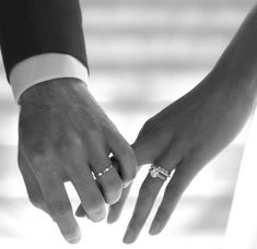 the bride and groom hold hands with their wedding rings on their fingers in black and white