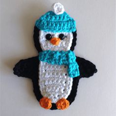 a crocheted penguin ornament with a blue hat and scarf on it