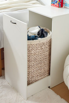 a basket with clothes in it is sitting on the floor next to a white bed