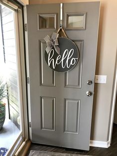 a door with a hello sign hanging on it's side and a potted plant next to it