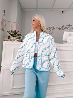 Wrap yourself in floral perfection with the Blue Floral Crest Quilted Jacket from Sassy Shortcake. This ivory, quilted jacket features a playful blue floral pattern and side pockets, all finished off with a blue lined hem. Stay warm and stylish in this fun jacket. content: 100% nylon care: hand wash cold fits true to size, model wearing size small Blue Floral Print Cotton Outerwear, Blue Cotton Floral Print Outerwear, Spring Floral Print Outerwear For Loungewear, Blue Outerwear For Spring Loungewear, White Quilted Jacket For Spring, White Quilted Jacket With Pockets For Spring, Spring Cotton Quilted Jacket, Blue Quilted Spring Outerwear, Sassy Shortcake