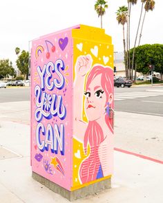 there is a pink and yellow box on the side of the street that says yes you can