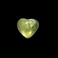 a green heart shaped glass object on a black background with the word love written in it