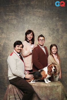 a group of people posing for a photo with a dog on top of a table