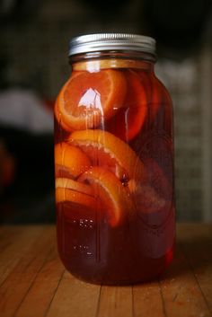 a jar filled with orange slices on top of a wooden table